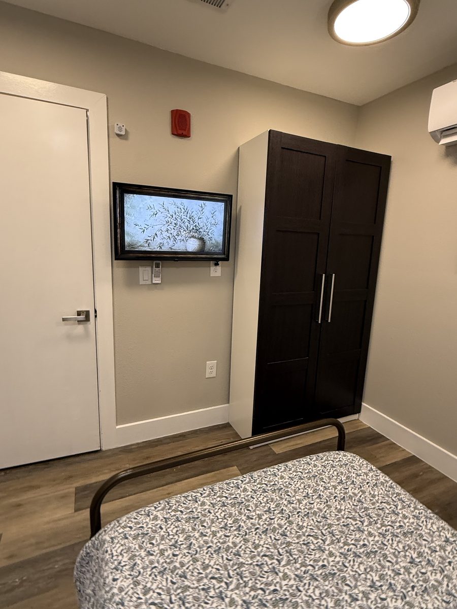 Resident room with framed TV and dark wardrobe